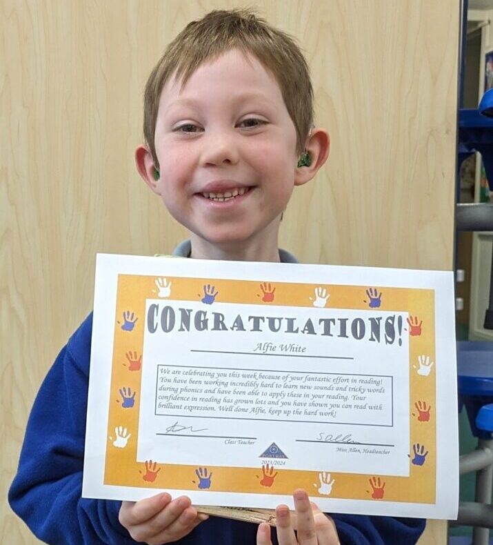 Alfie holding certificate and smiling.